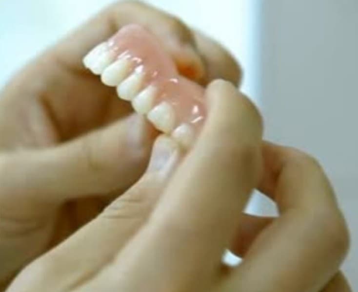 Prótese dentária sendo segurada com as duas mãos