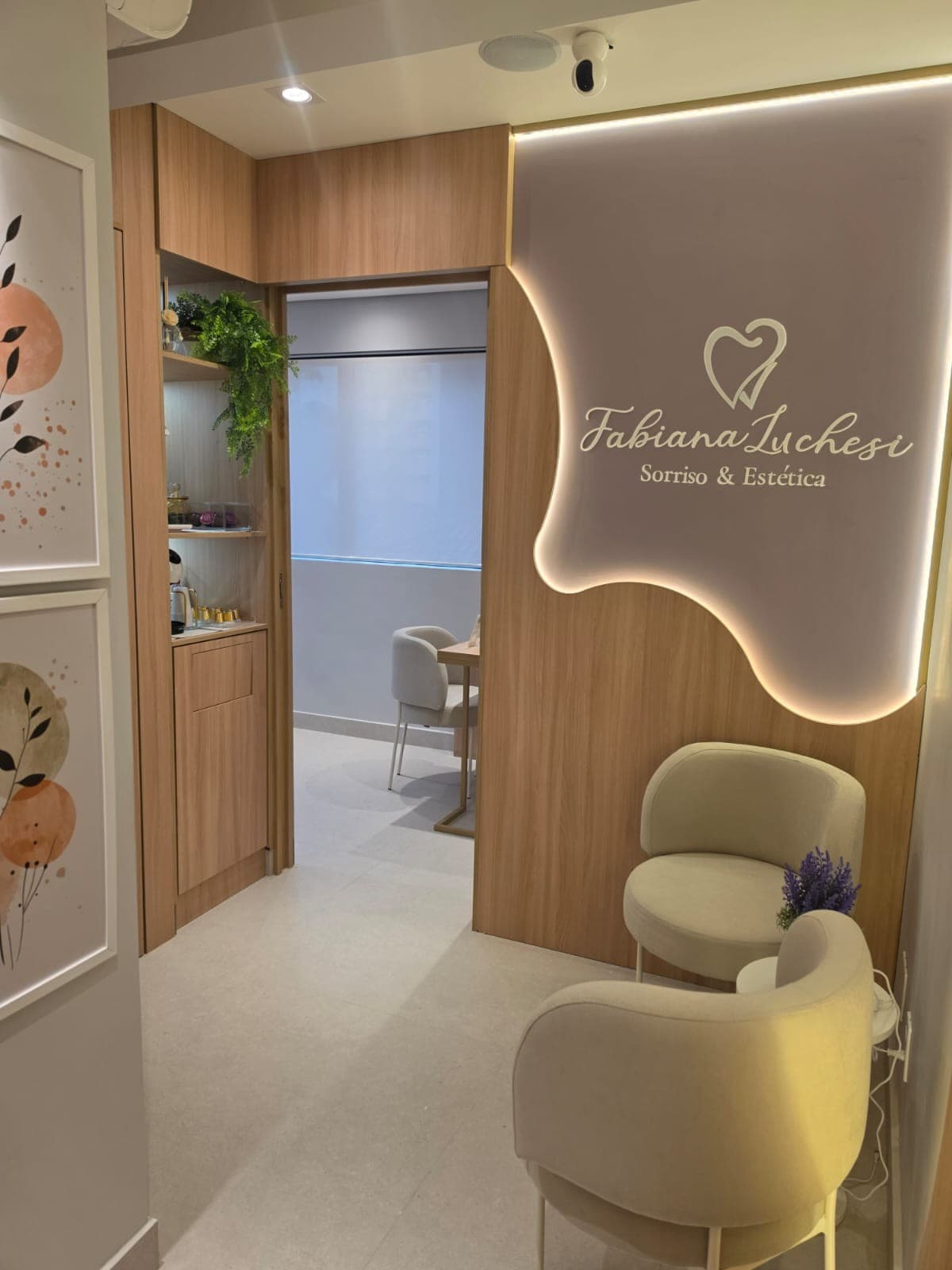 Recepção do consultório com o logo Fabiana Luchesi Sorriso & Estética na parede iluminada